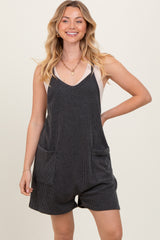 woman wearing a black and white striped overall romper with front pockets and a v-neckline