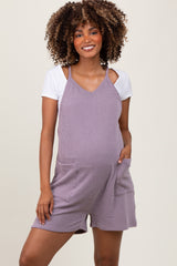 woman wearing a lavender striped maternity romper with pockets and a white t-shirt underneath, showing her baby bump