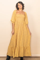 woman wearing a yellow floral maxi dress with puff sleeves and a tiered skirt