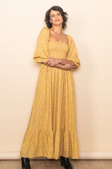 woman wearing a yellow floral maxi dress with puff sleeves and a tiered skirt