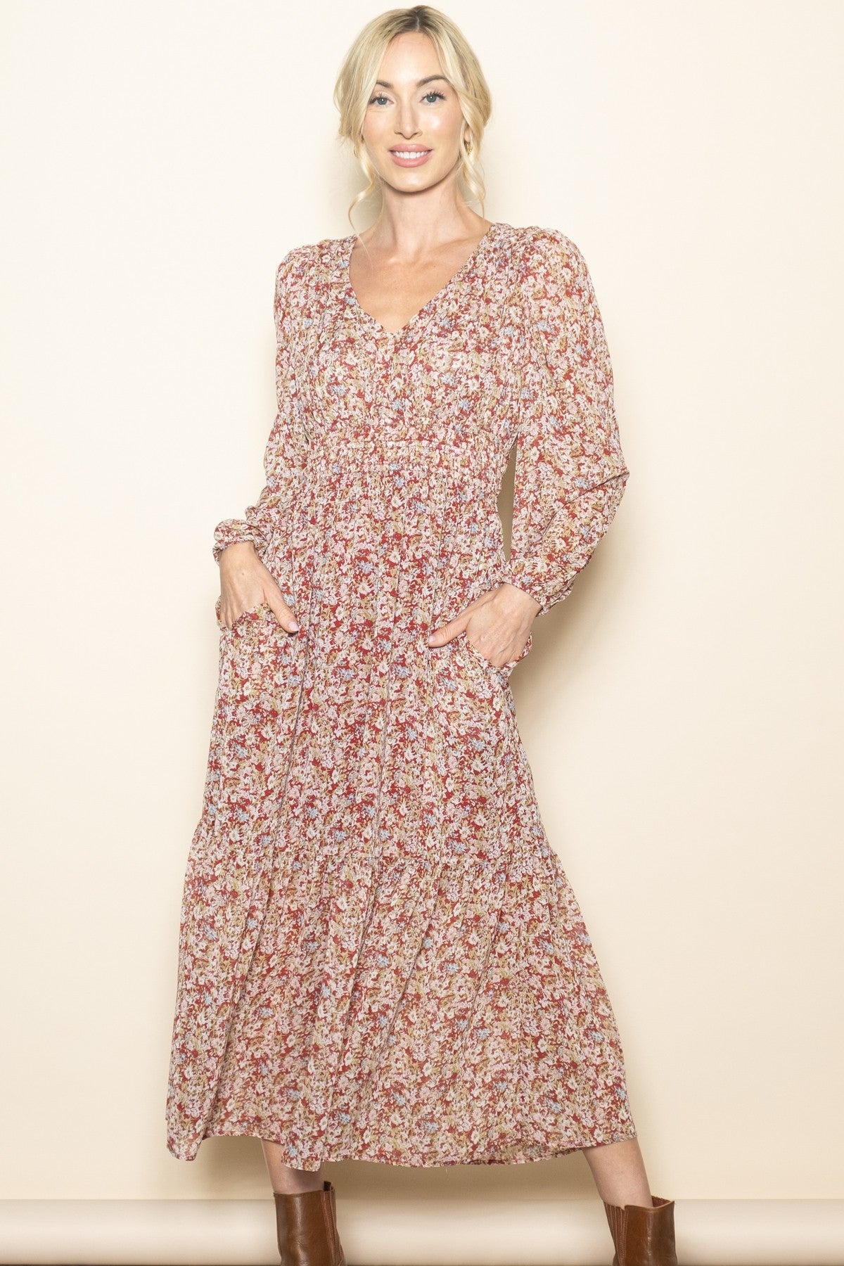 woman wearing a long sleeve floral maxi dress with a v-neck and pockets, styled with brown ankle boots