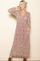 woman wearing a long floral print maxi dress with long sleeves and pockets, smiling against a neutral background