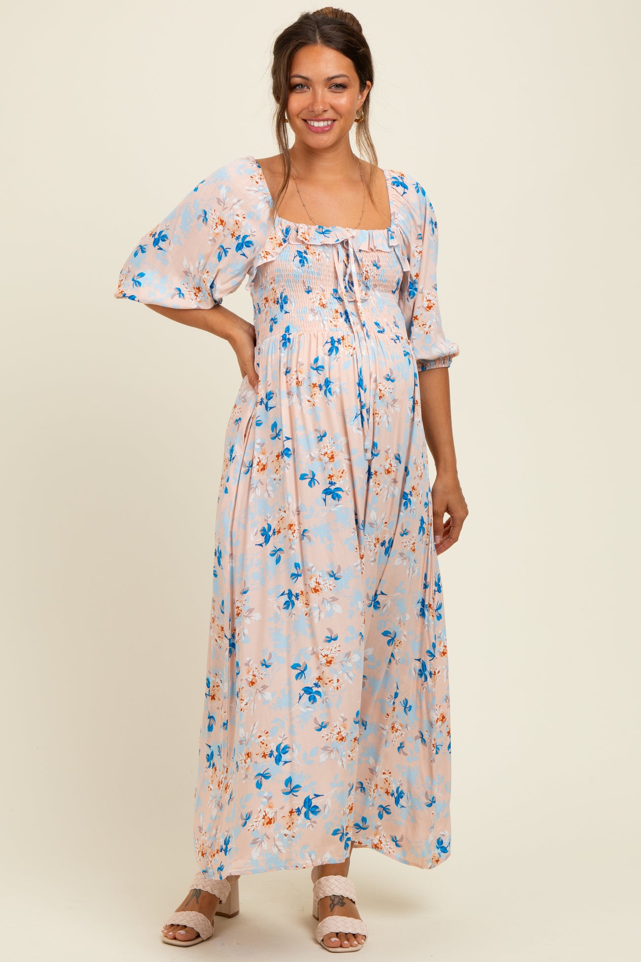 woman wearing a floral print maternity maxi dress with puff sleeves and a baby bump visible