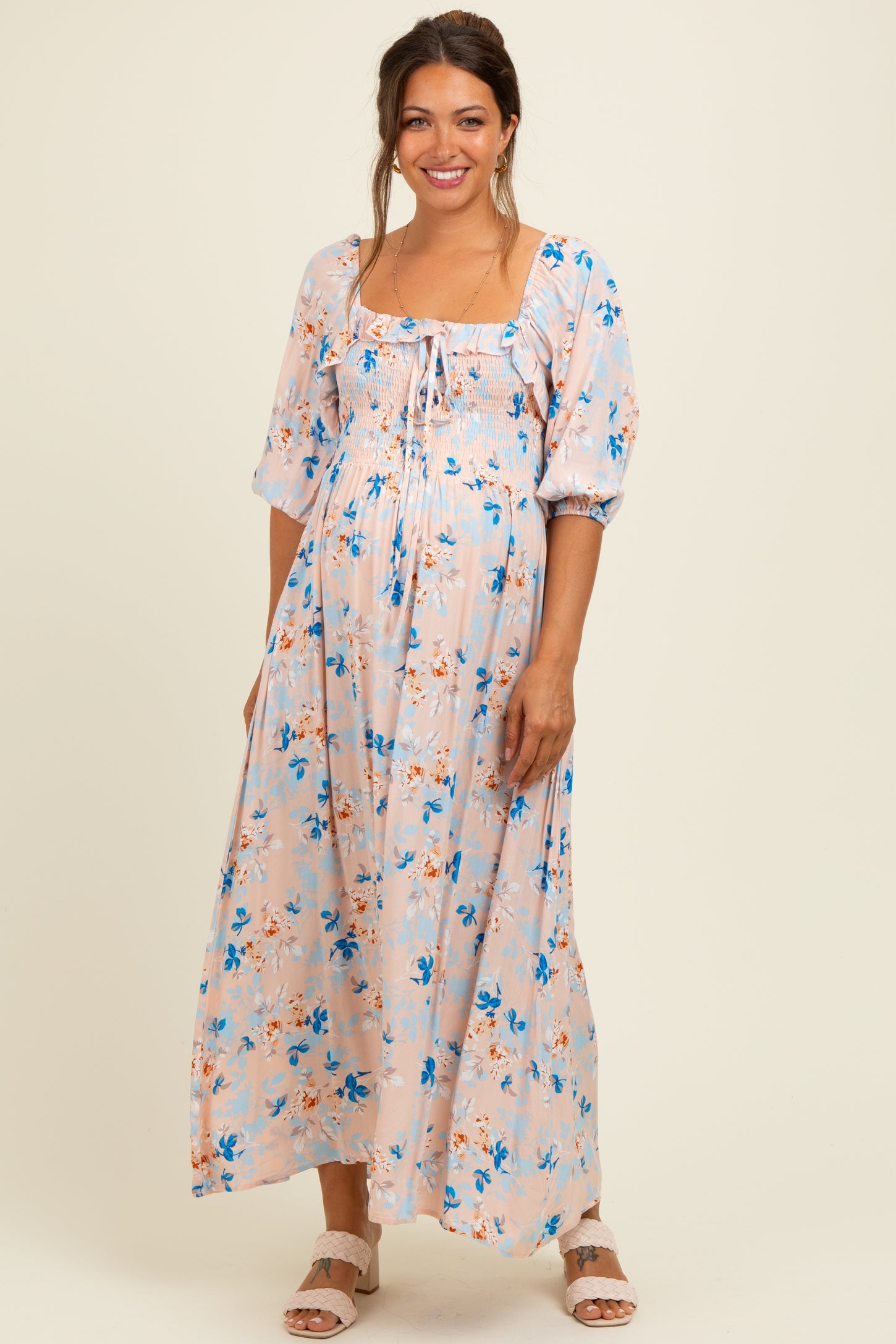 woman wearing a floral print long sleeve maternity maxi dress with a square neckline and a baby bump visible