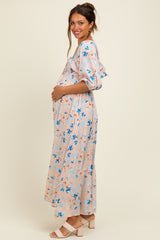 woman wearing a light pink floral maternity maxi dress and holding her baby bump