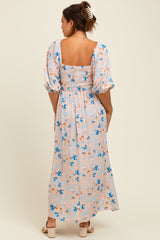 woman wearing a floral maternity maxi dress with puff sleeves and a smocked bodice, showing the back view