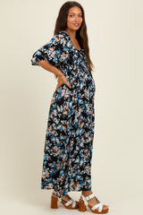 woman wearing a black floral maternity maxi dress with short sleeves and a visible baby bump