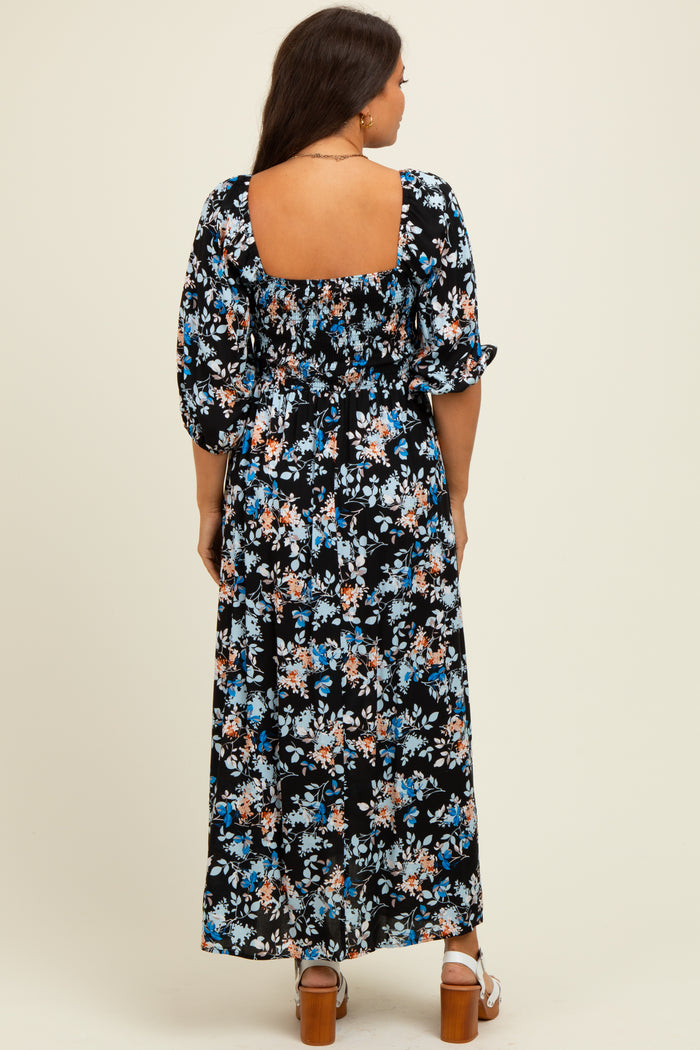 woman wearing a black floral maternity maxi dress with a square neckline and puff sleeves, showing a baby bump