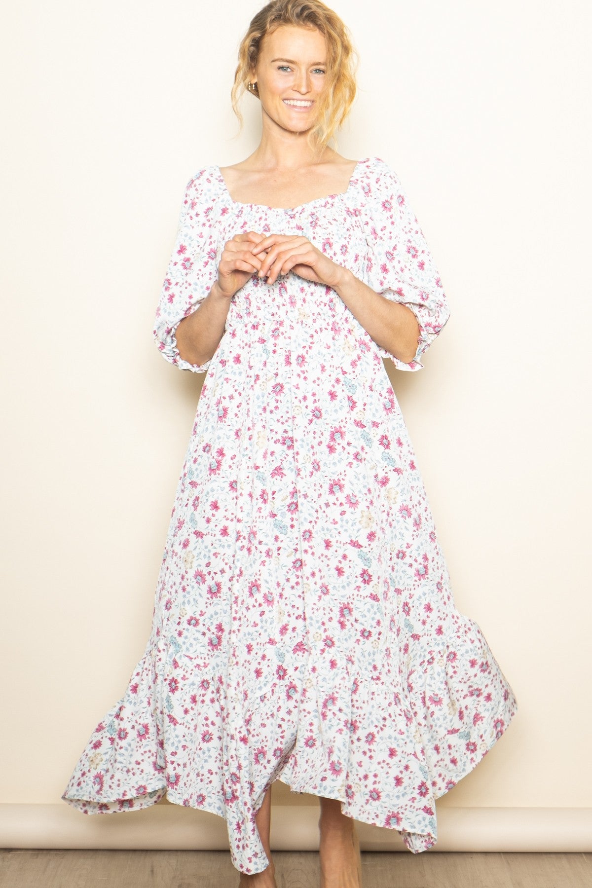 woman wearing a white floral maxi dress with a square neckline and three-quarter sleeves