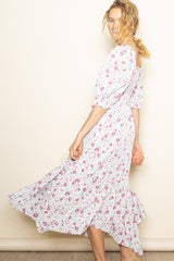 woman wearing a floral midi dress with puff sleeves and a ruffled hem, twirling against a light background