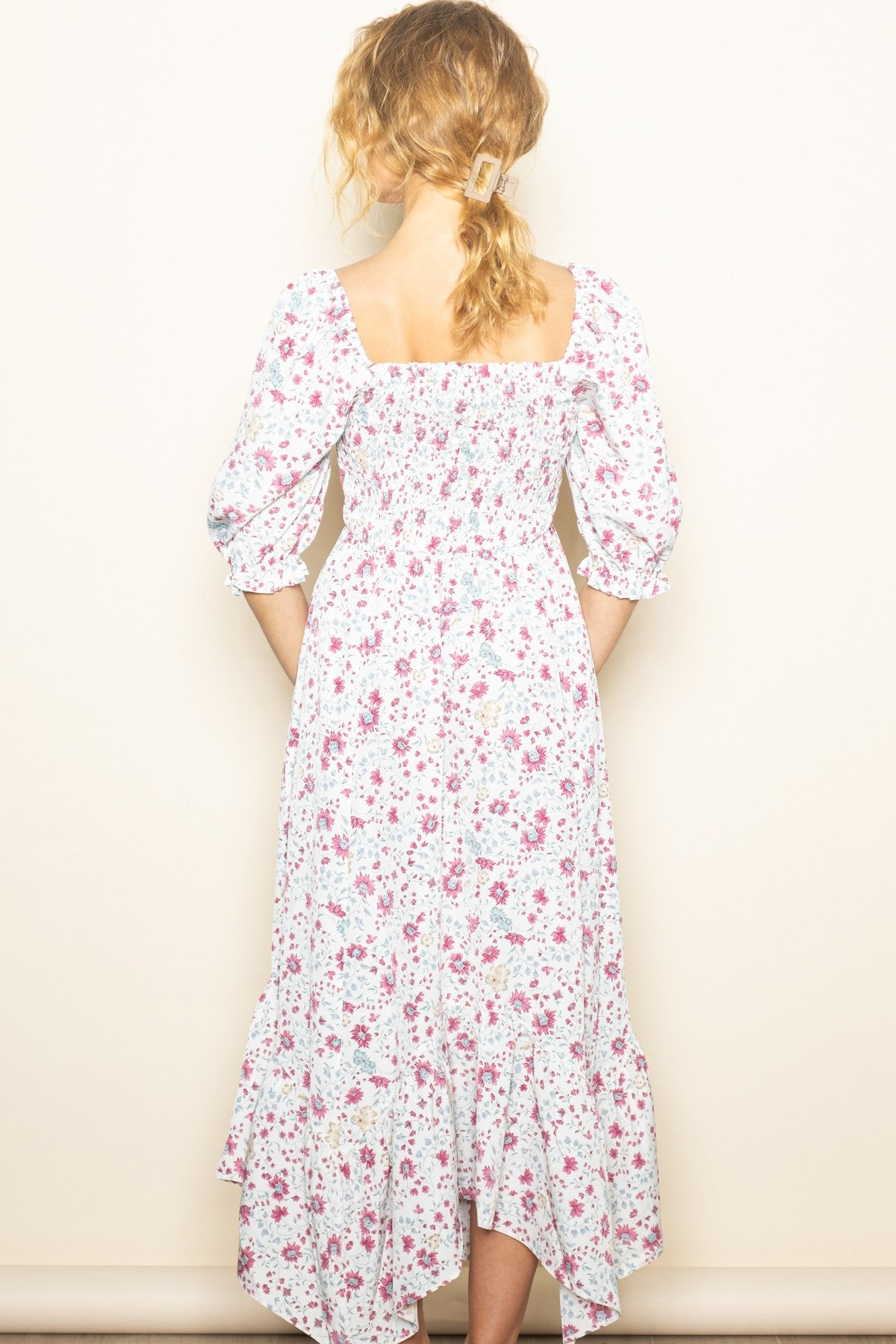 woman wearing a white floral midi dress with puff sleeves and a tiered hem, viewed from the back