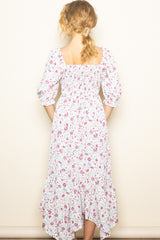woman wearing a white floral midi dress with puff sleeves and a tiered hem, viewed from the back