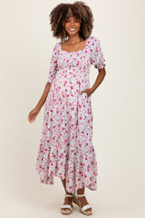 woman wearing a floral print maternity dress with a smocked bodice, ruffled hem, and pockets, featuring a visible baby bump