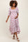 woman wearing a floral print maternity dress with a square neck, puff sleeves, and a flowing skirt, holding her baby bump