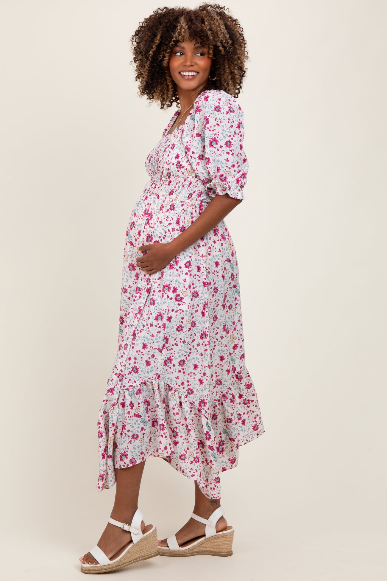 woman wearing a floral maternity dress with puff sleeves and a ruffled hem, showing her baby bump