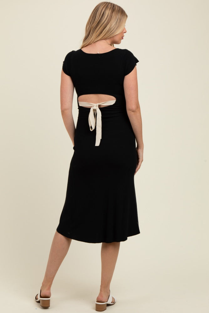 woman wearing a black maternity dress with a back cutout and tie detail, highlighting her baby bump