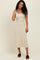 woman wearing a beige ribbed midi dress with a scoop neckline and a fitted silhouette, standing and smiling