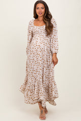 woman wearing a floral maternity maxi dress with puff sleeves and a ruffled hem