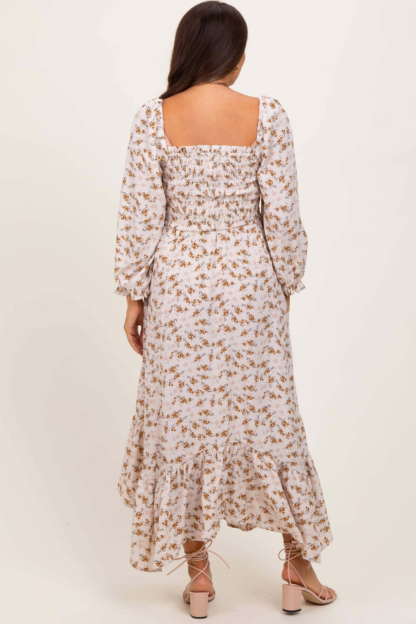 woman wearing a floral print long sleeve maternity dress with a square neckline and ruffled hem, showing a baby bump