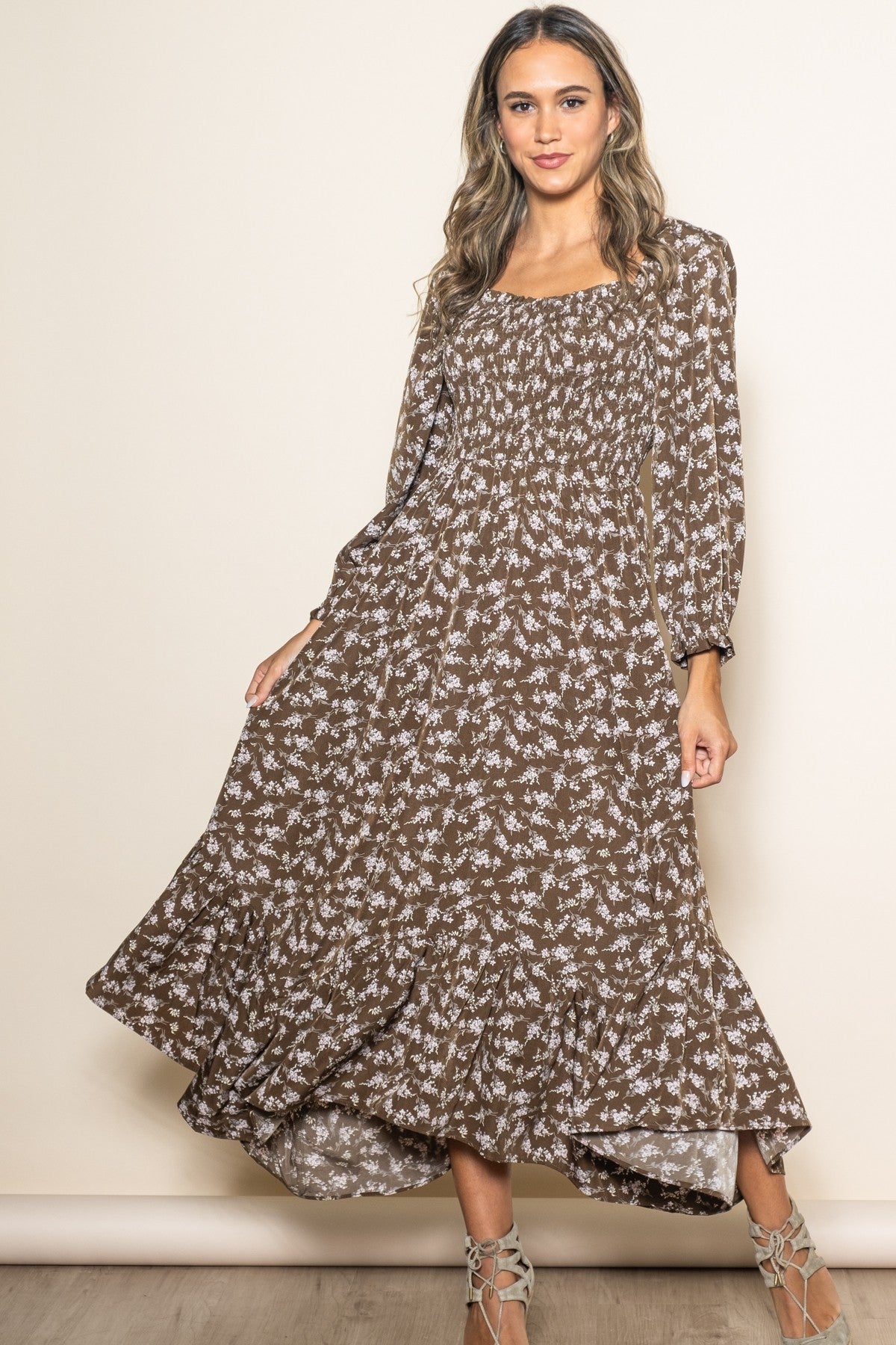 woman wearing a brown floral maxi dress with long sleeves and a tiered hemline