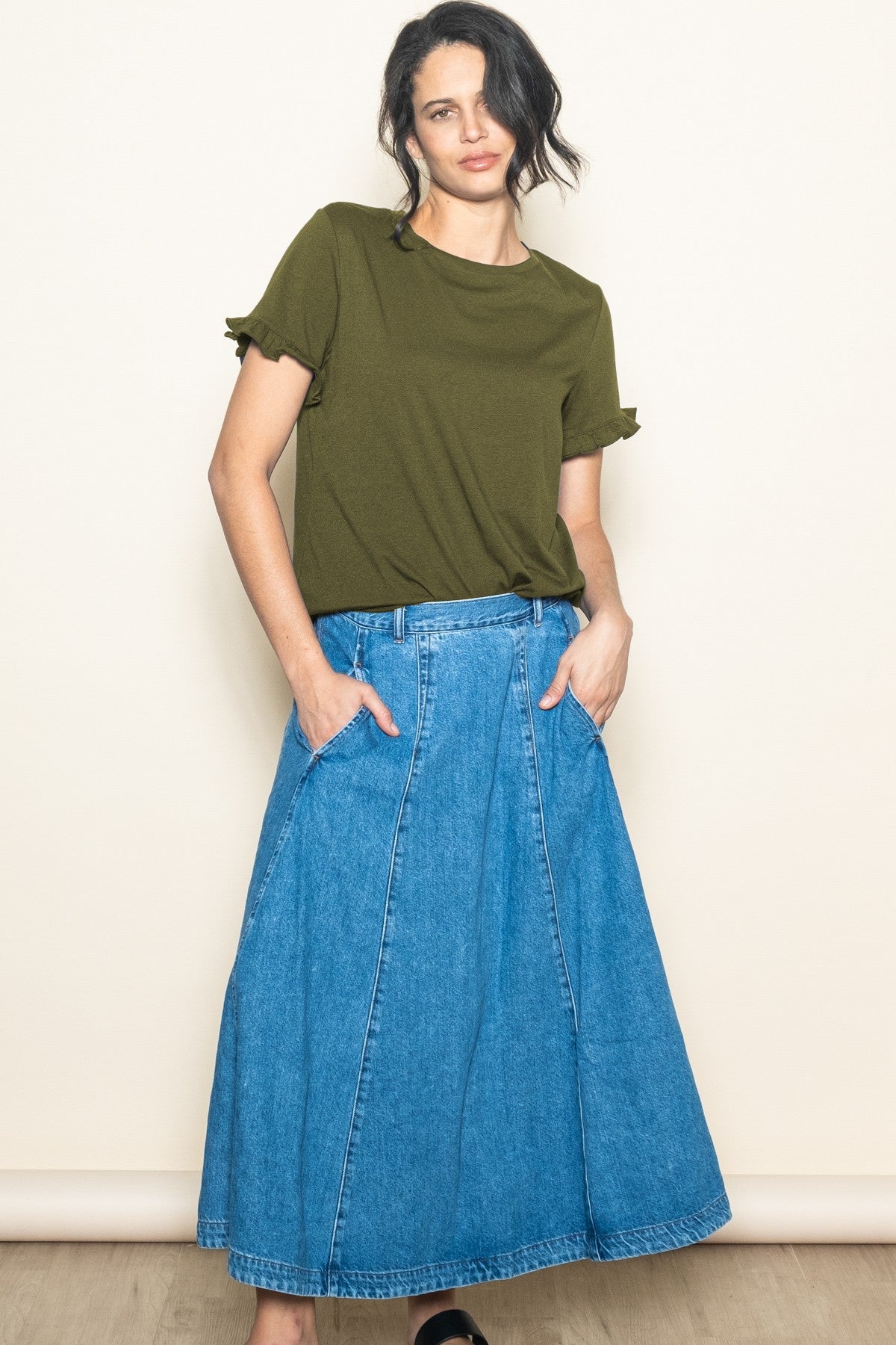 woman wearing an olive green t-shirt with ruffle sleeves and a long denim skirt with pockets