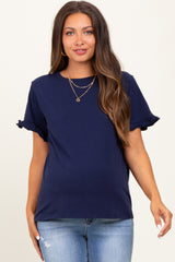woman wearing a navy blue maternity top with ruffled sleeves and a visible baby bump