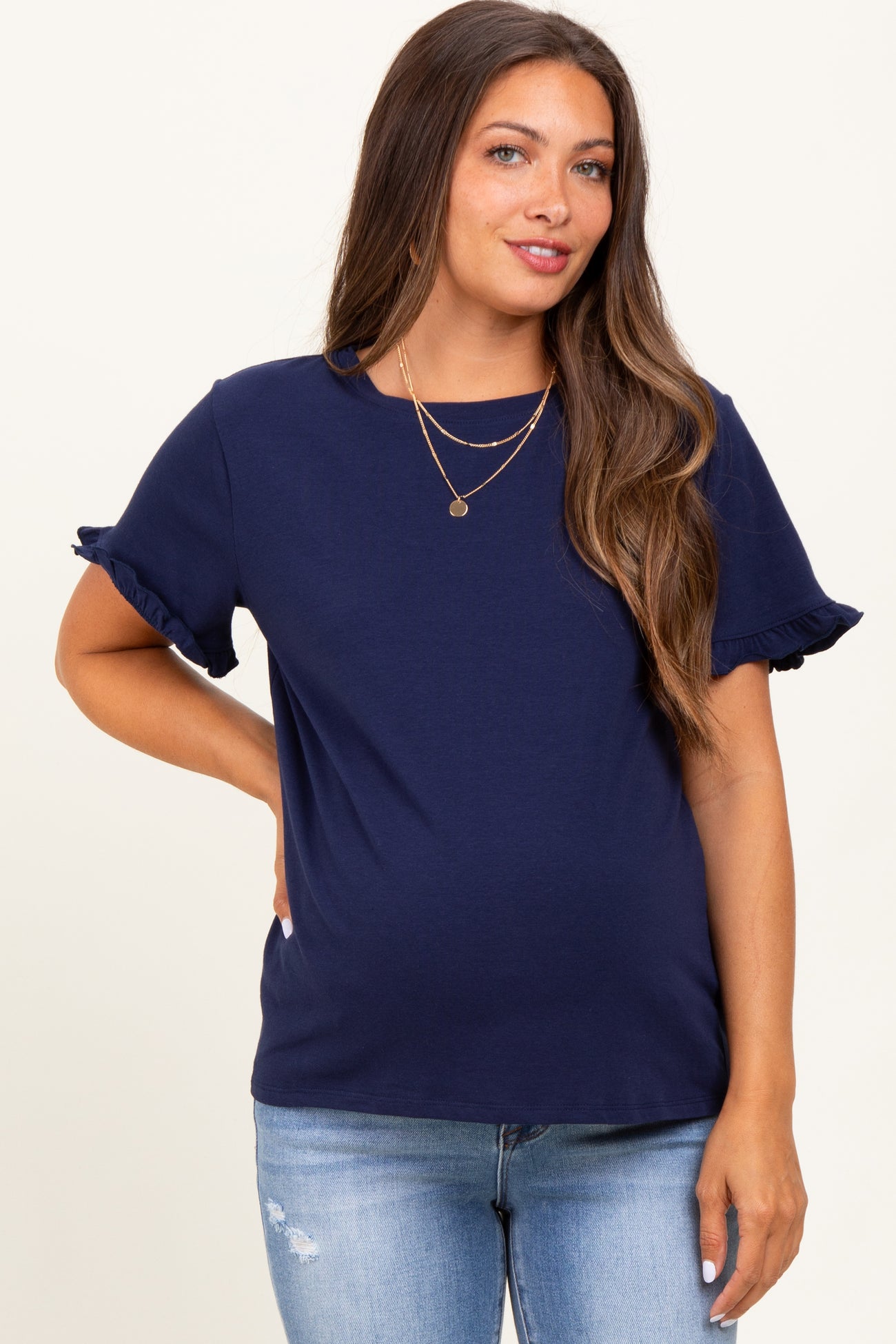 woman wearing a navy blue maternity top with ruffle sleeves and a visible baby bump