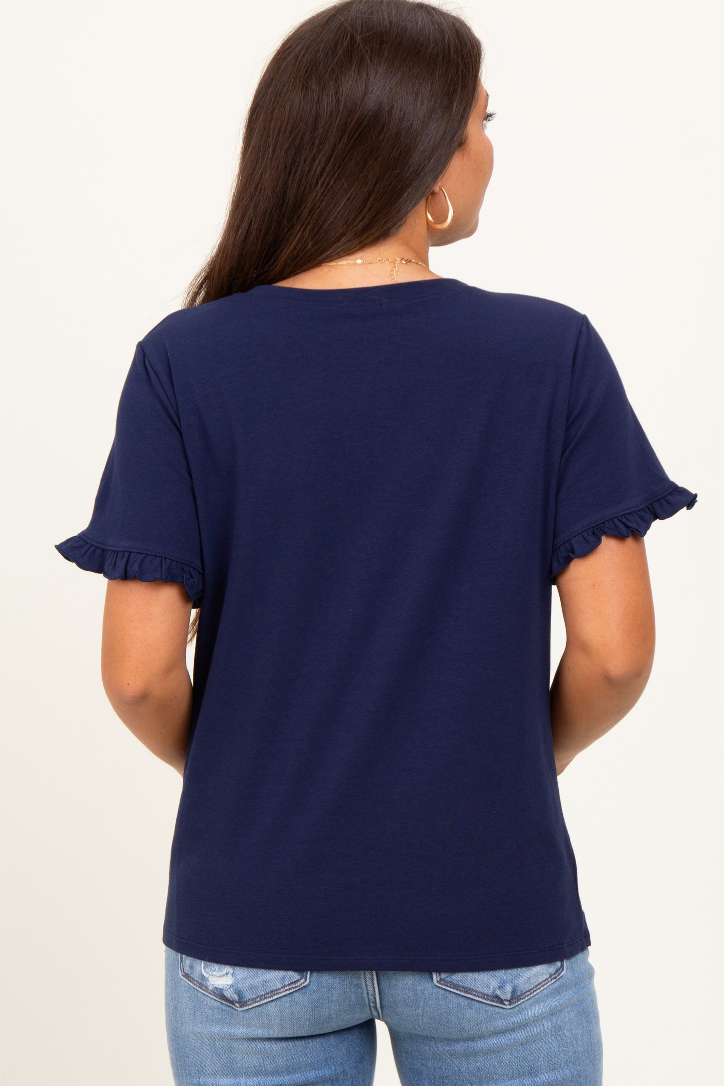 woman wearing a navy blue maternity top with ruffled sleeves and a relaxed fit, showing her back view