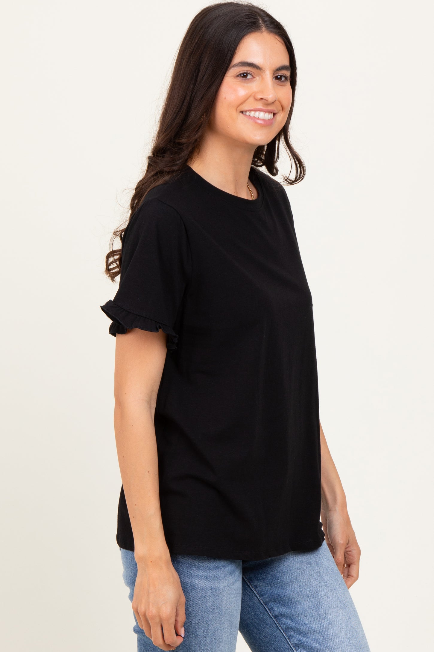 woman wearing a black short sleeve t-shirt with ruffle details, paired with blue jeans