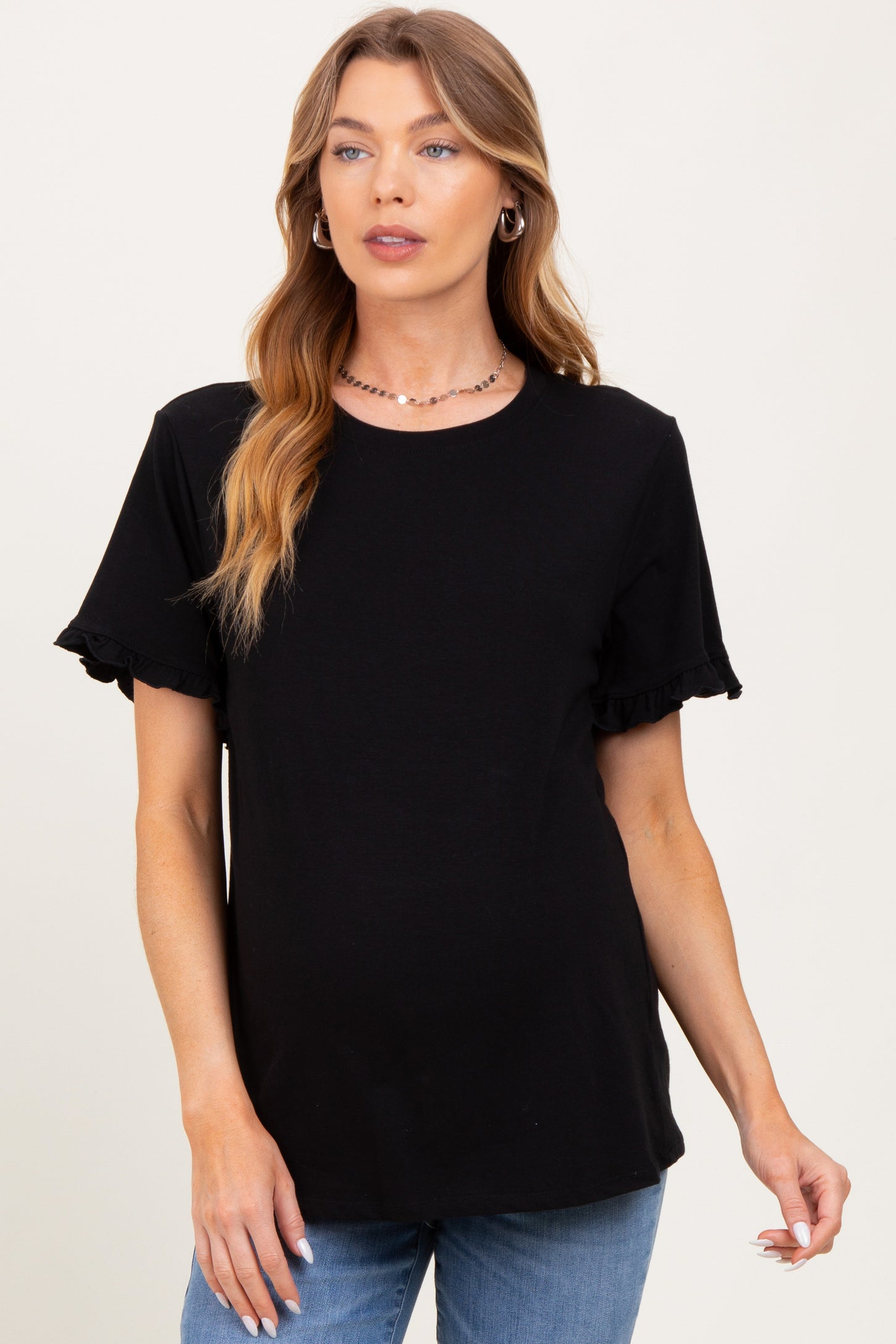 woman wearing a black maternity top with ruffled short sleeves and a visible baby bump
