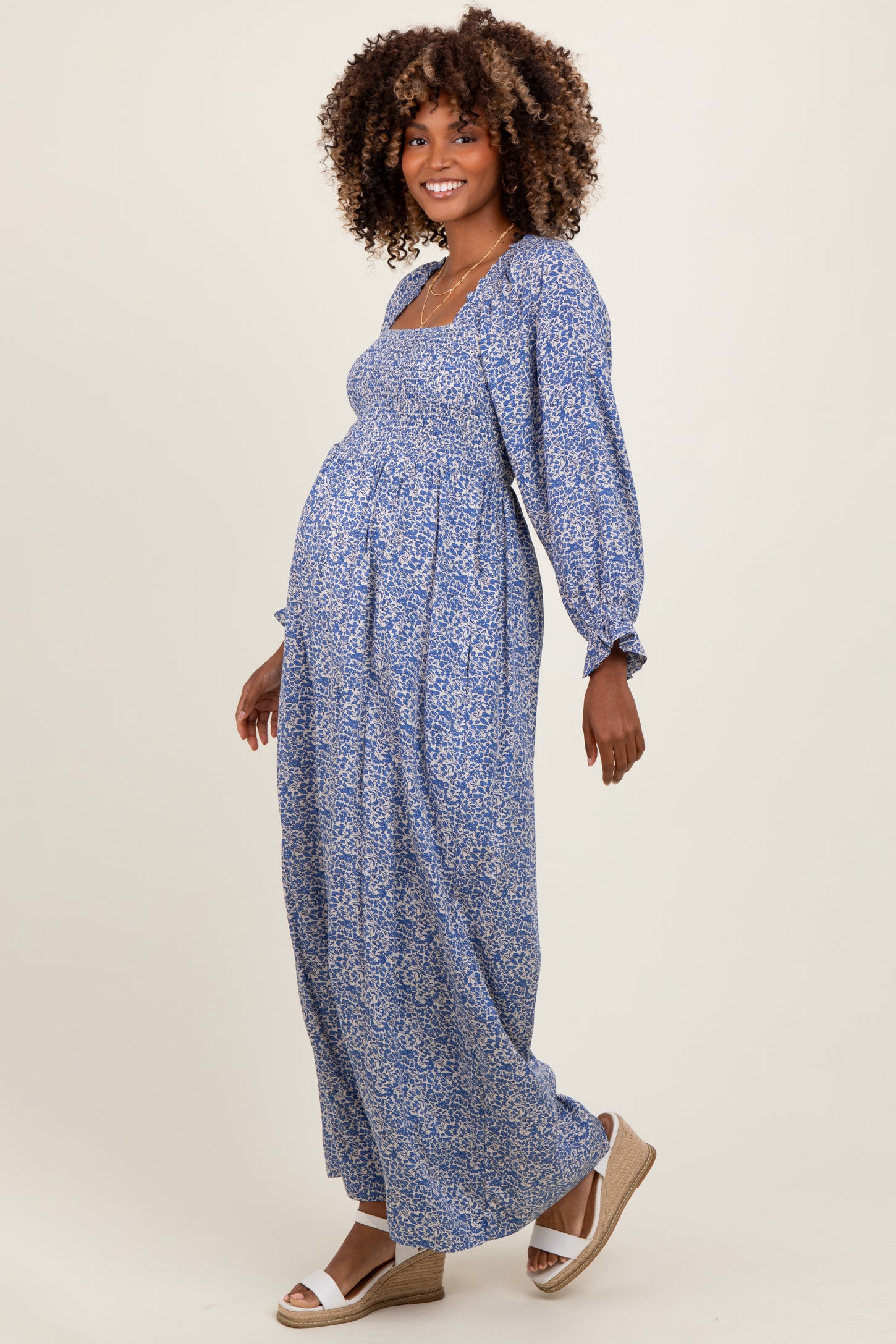 woman wearing a blue floral maternity maxi dress with puff sleeves and a visible baby bump