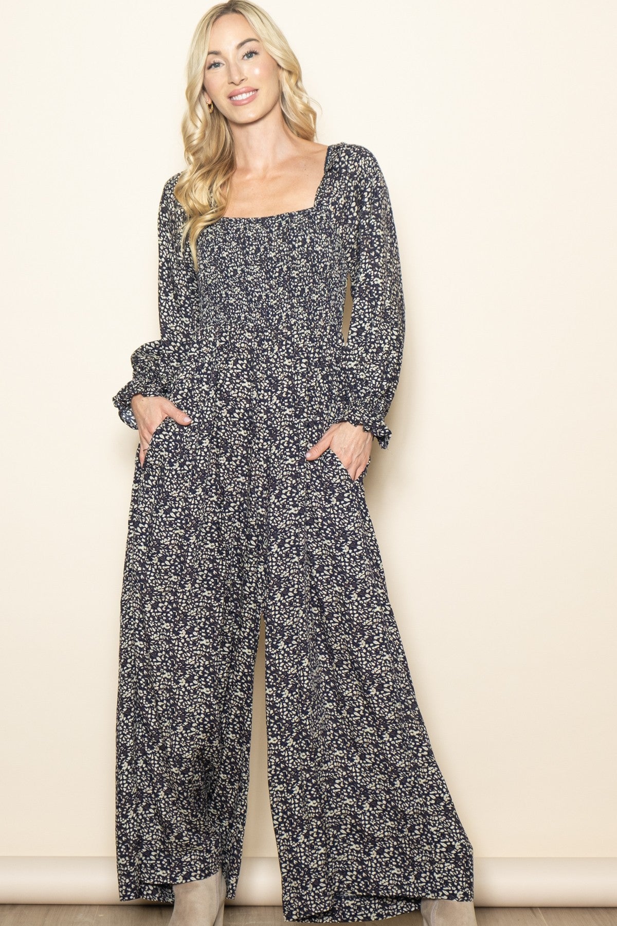 woman wearing a black floral long sleeve jumpsuit with pockets and a square neckline