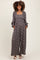 woman wearing a floral print black maternity jumpsuit with long sleeves and pockets, showing her baby bump