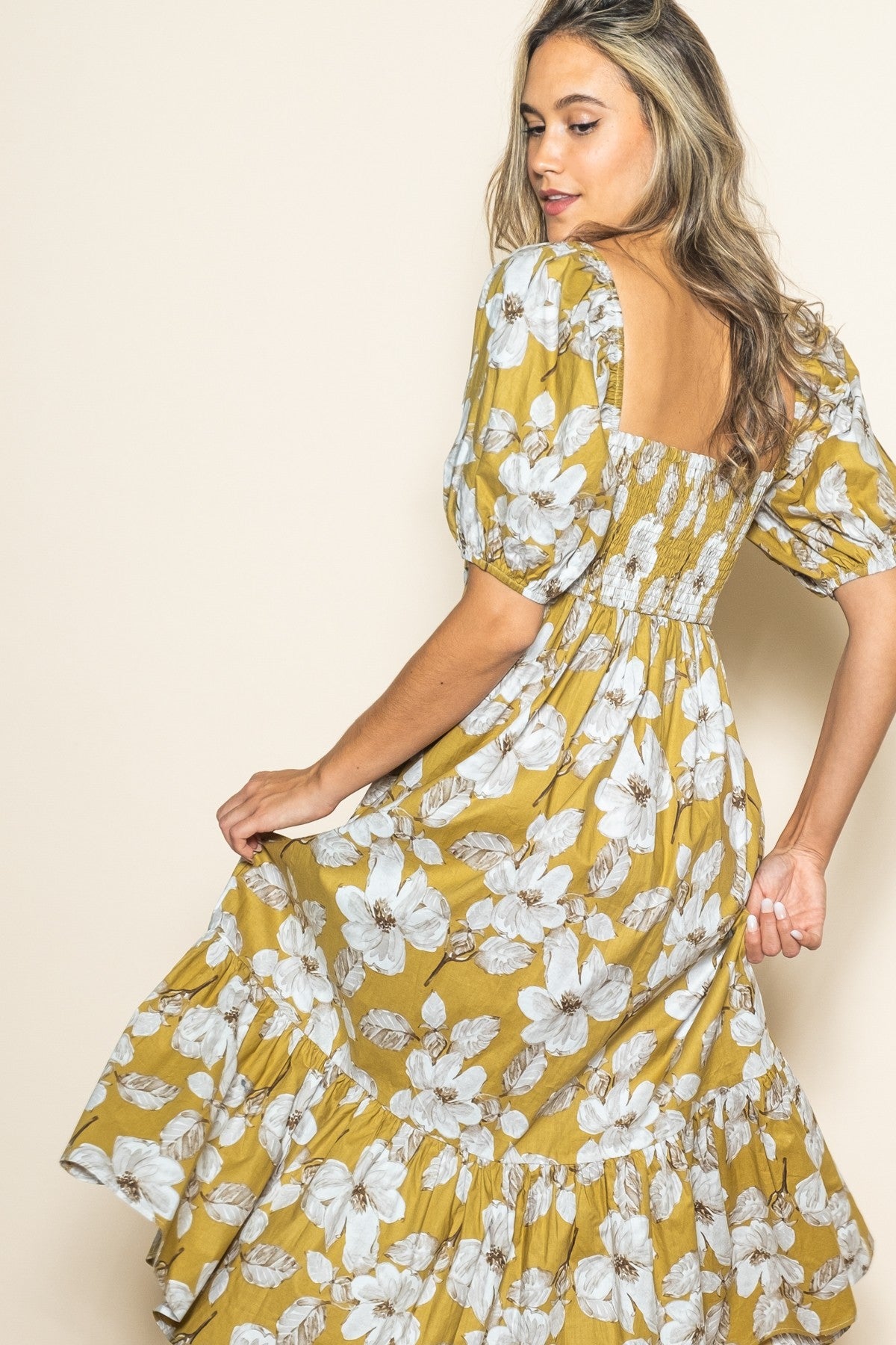 woman wearing a mustard floral print dress with puff sleeves and a tiered ruffle hem