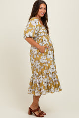 woman wearing a floral mustard maternity dress with puff sleeves and a ruffled hem, displaying her baby bump