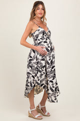 woman wearing a black and white floral maternity dress with a high-low hem and holding her baby bump