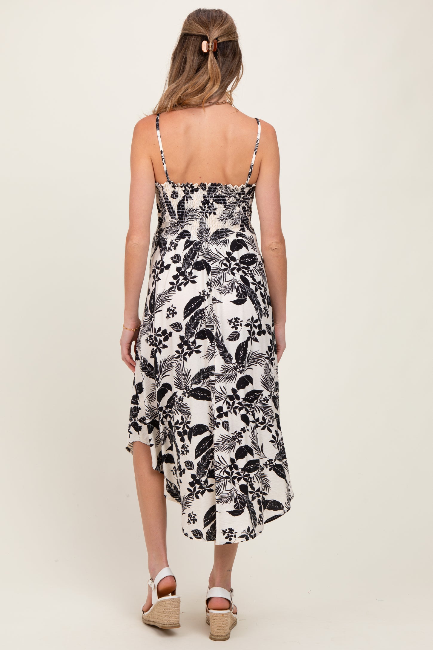 woman wearing a black and white floral print maternity dress with adjustable straps and a flowy hem, showing a baby bump
