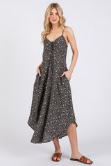 woman wearing a black floral midi dress with adjustable straps and pockets, styled with brown sandals
