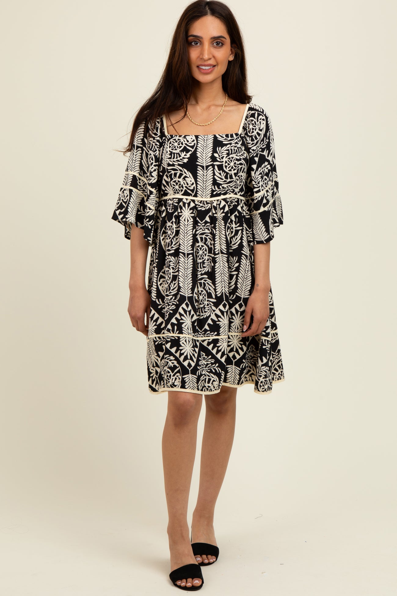 woman wearing a black and white patterned short dress with flutter sleeves and a square neckline