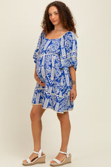 woman wearing a blue and white patterned maternity dress with a baby bump, styled with white wedge sandals