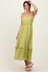 woman wearing a light green ruffled strap maxi dress with a tiered skirt and a fitted waist
