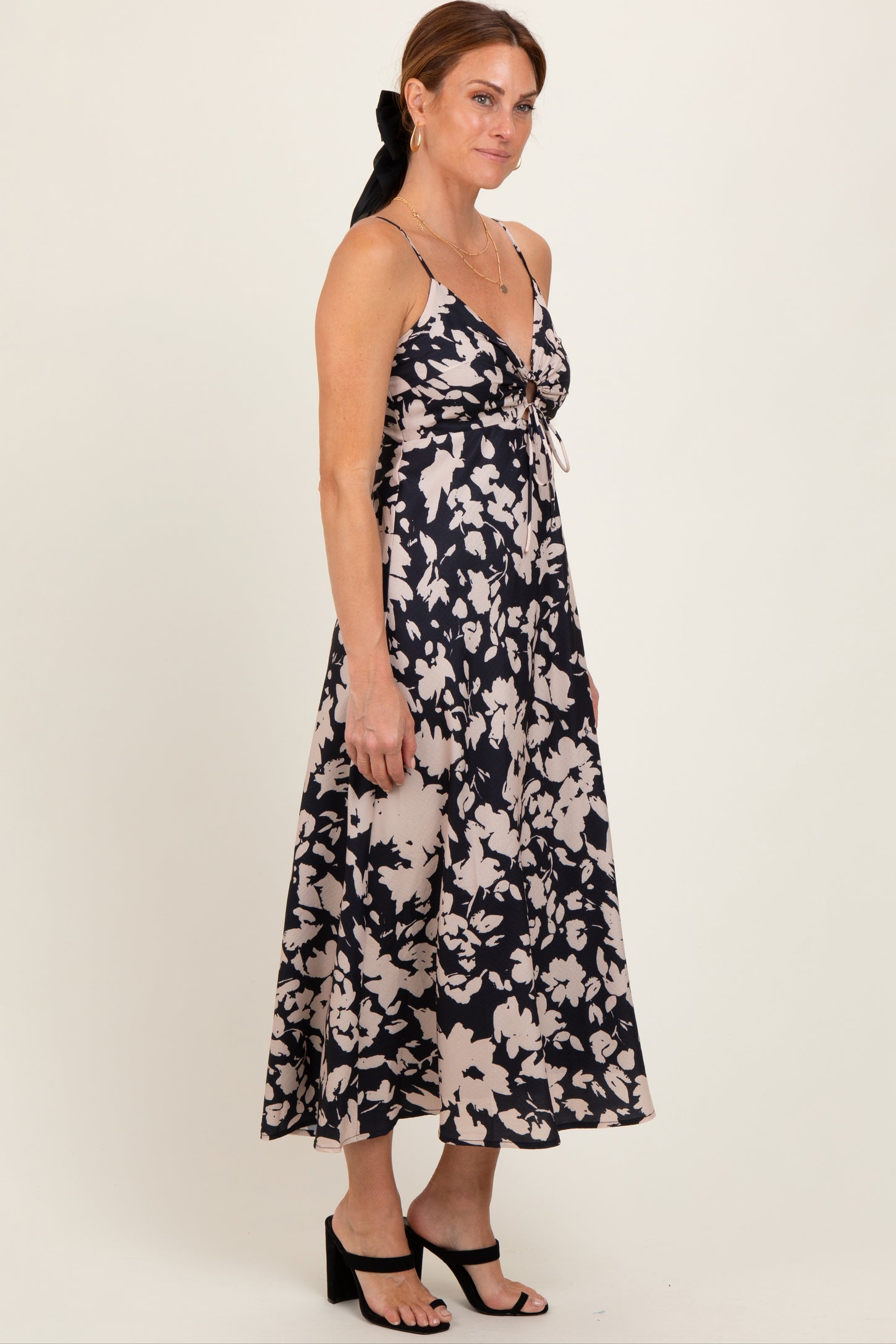woman wearing a navy blue and cream floral print spaghetti strap maxi dress with a fitted bodice and flowy skirt