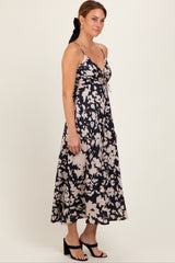 woman wearing a navy blue and cream floral print spaghetti strap maxi dress with a fitted bodice and flowy skirt