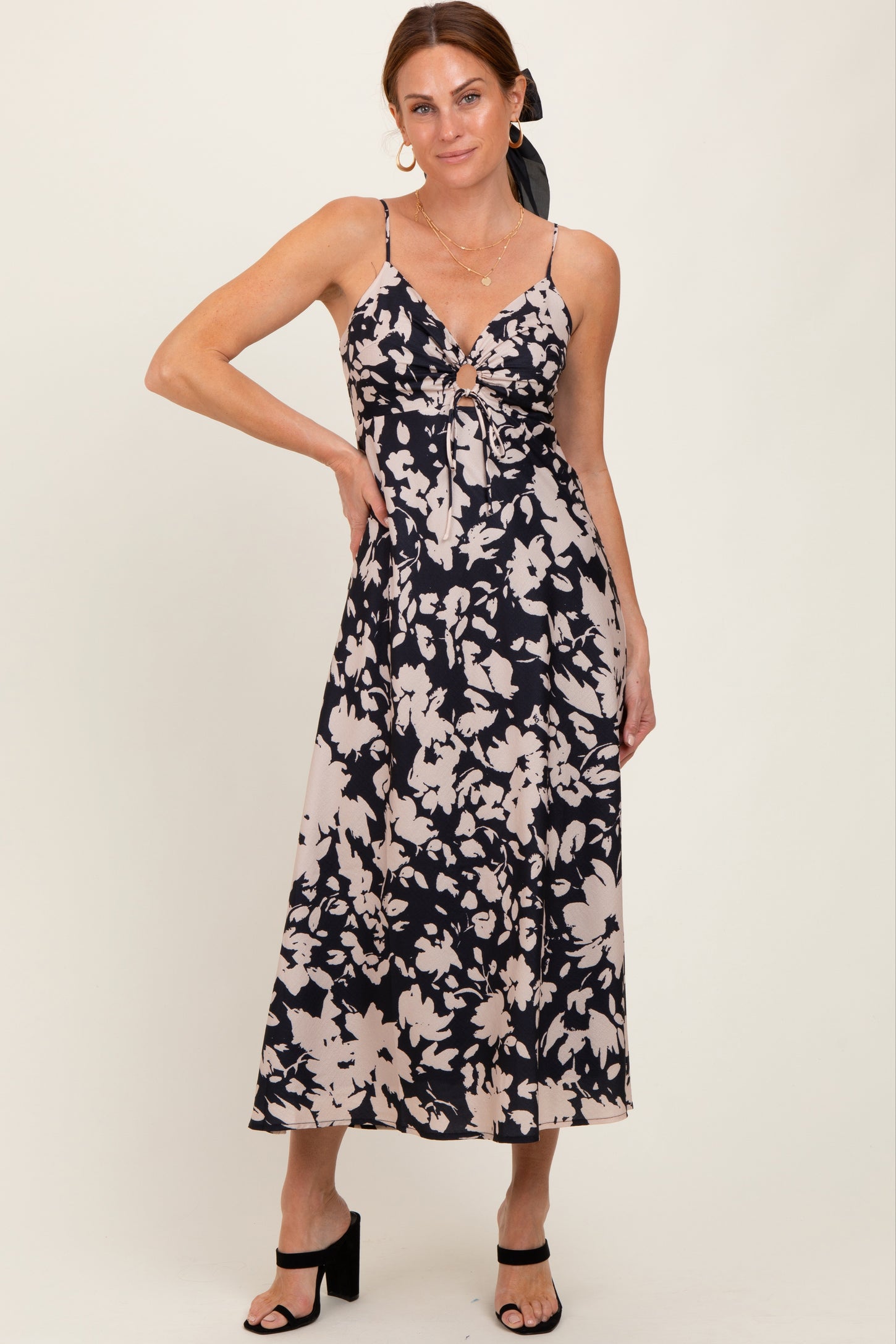 woman wearing a navy blue and cream floral midi dress with adjustable straps and a front tie detail