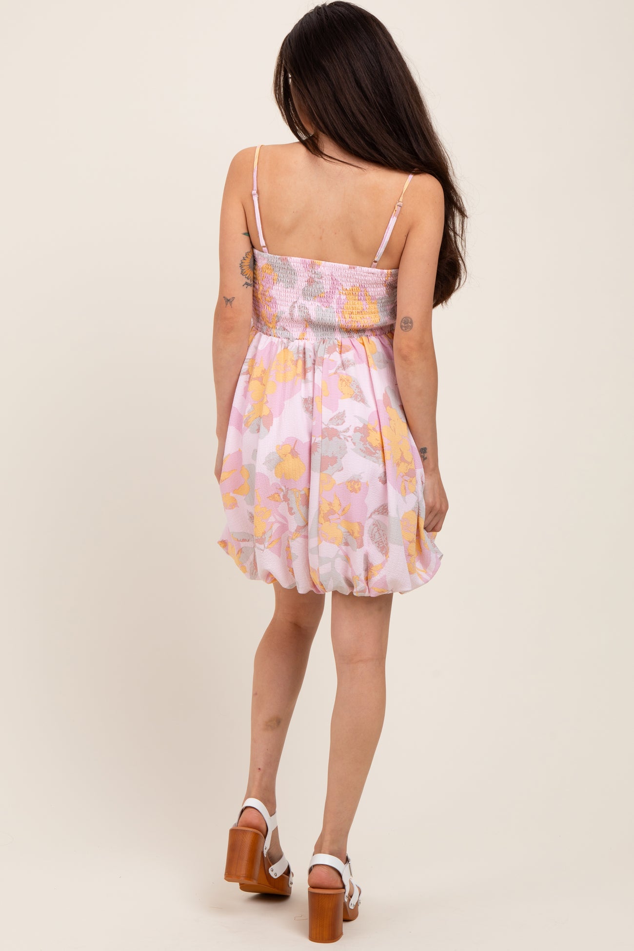 woman wearing a pink floral maternity dress with a smocked bodice and a flowy skirt, seen from the back