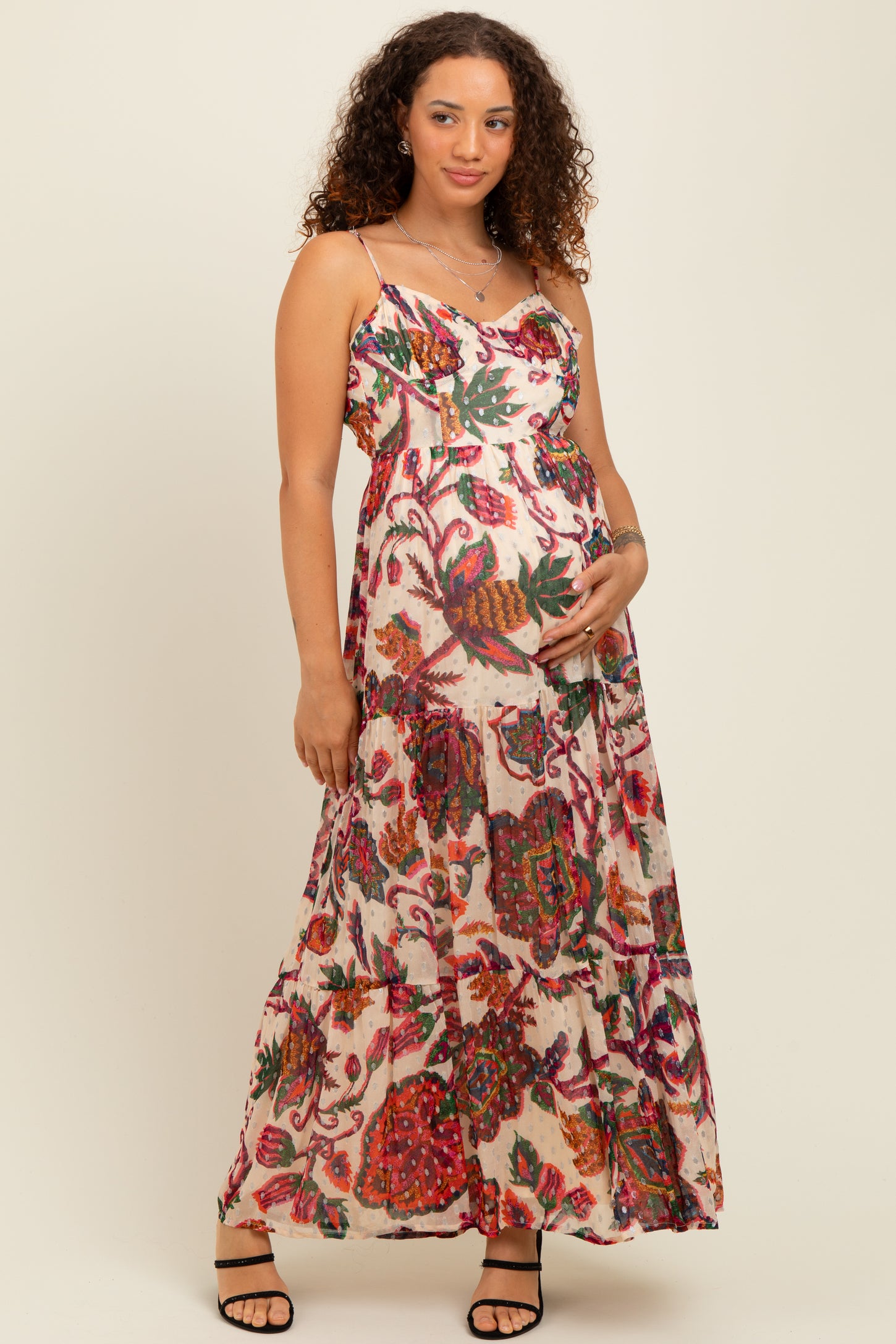 woman wearing a floral print maternity maxi dress and cradling her baby bump