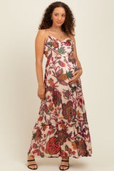 woman wearing a floral print maternity maxi dress and cradling her baby bump