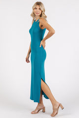 woman wearing a teal sleeveless maxi dress with side slits and a fitted silhouette