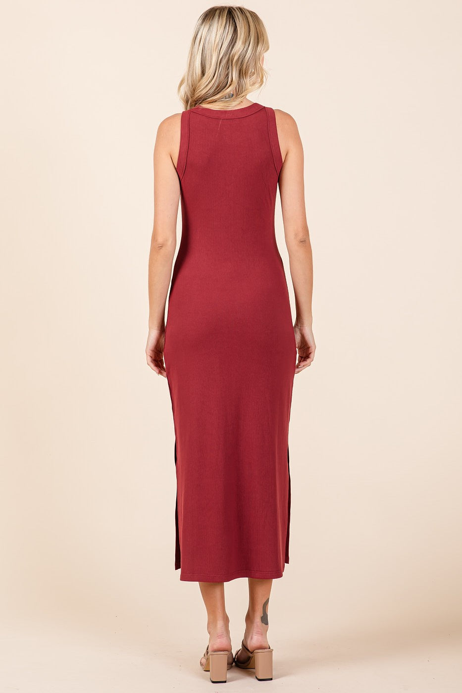 woman wearing a burgundy sleeveless maxi dress with side slits, showing the back view