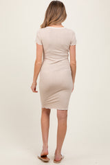 woman wearing a beige short sleeve maternity dress with a fitted silhouette and raw hem detail